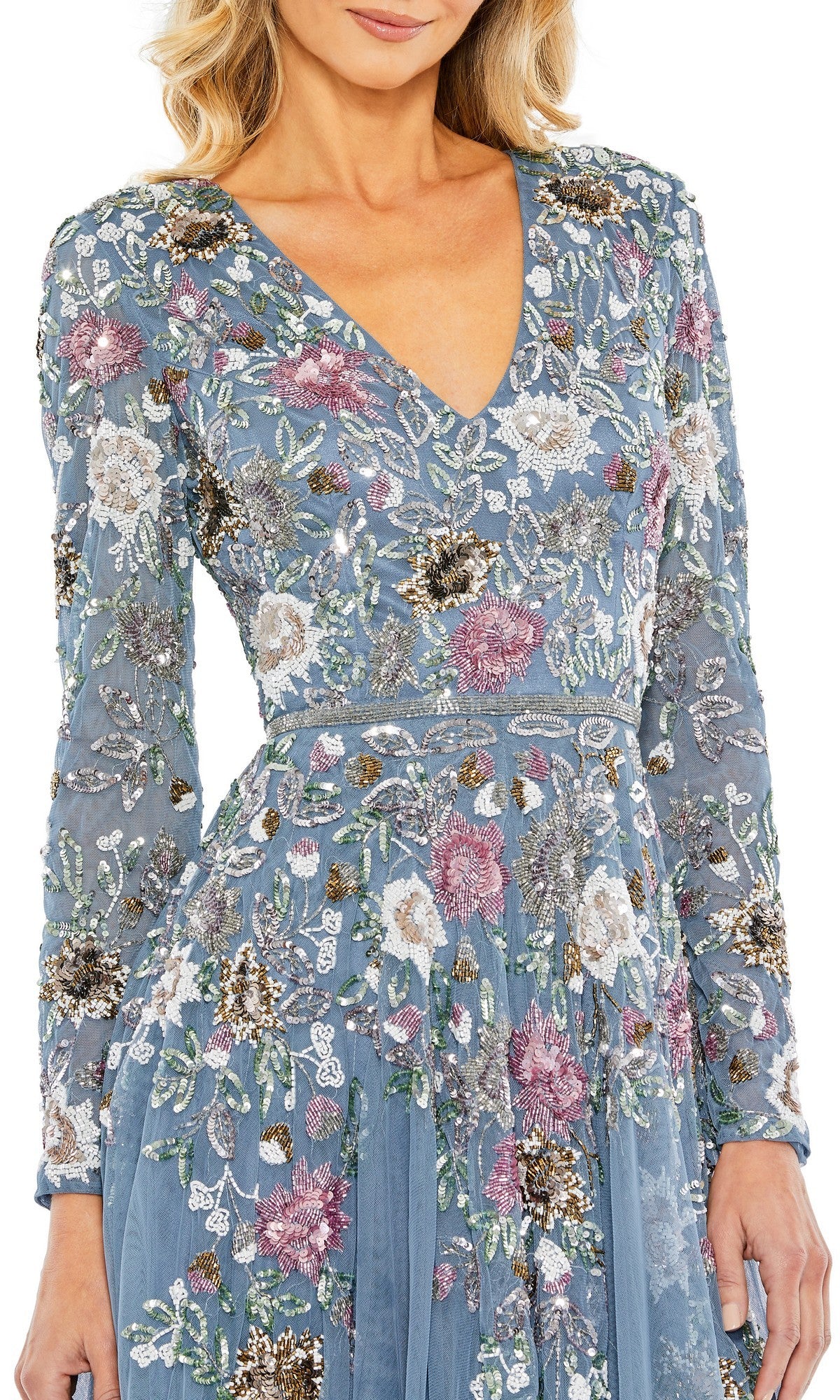 A woman wears the Mac Duggal 5594 Midi Wedding Guest Dress in blue, featuring long sleeves, a v-neckline, and elegant white, pink, and green floral embroidery—perfect for wedding guests.